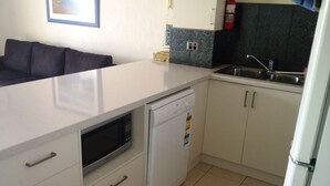 A compact kitchen with a dishwasher, a microwave, and a sink. - Noosa Keys Resort (Noosaville)