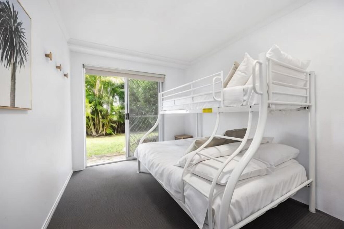A bunk bed room with a sliding glass door leading to a garden.
