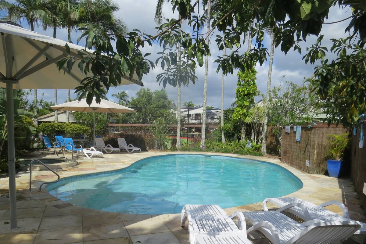 Una piscina con sillones de descanso y una sombrilla.