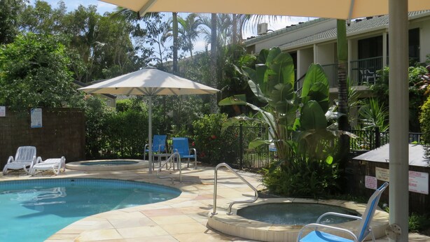A pool area with two hot tubs, lounge chairs, and an umbrella. - Noosa Keys Resort (Noosaville)