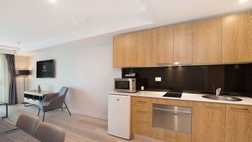 A modern kitchen with wooden cabinets, a microwave, a dishwasher, and a dining area with a table and chairs.