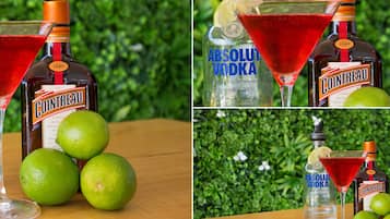 A bottle of Cointreau and a bottle of Absolut Vodka with limes and a martini glass.