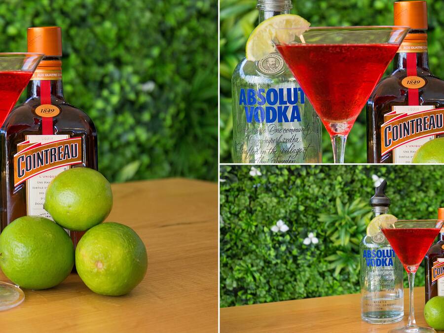 A bottle of Cointreau and a bottle of Absolut Vodka with limes and a martini glass.