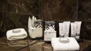 A bathroom with a marble floor, a towel, a shower caddy, and toiletries.