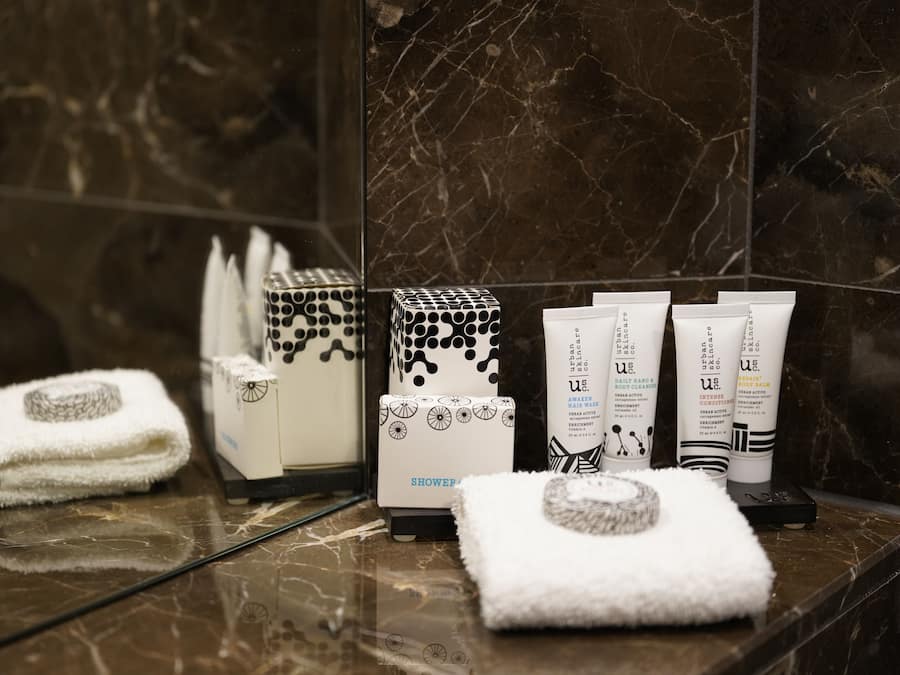 A bathroom with a marble floor, a towel, a shower caddy, and toiletries.