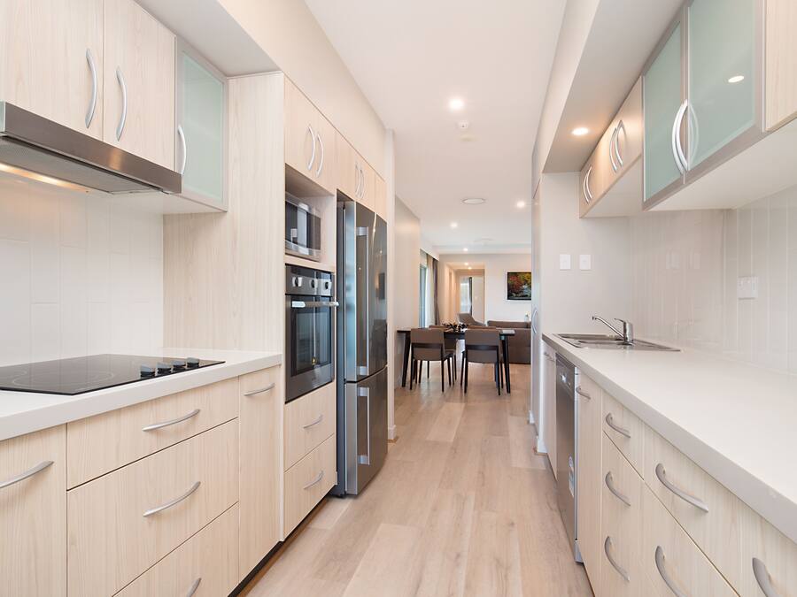Una cocina moderna con armarios de madera clara, electrodomésticos de acero inoxidable y una isla central.