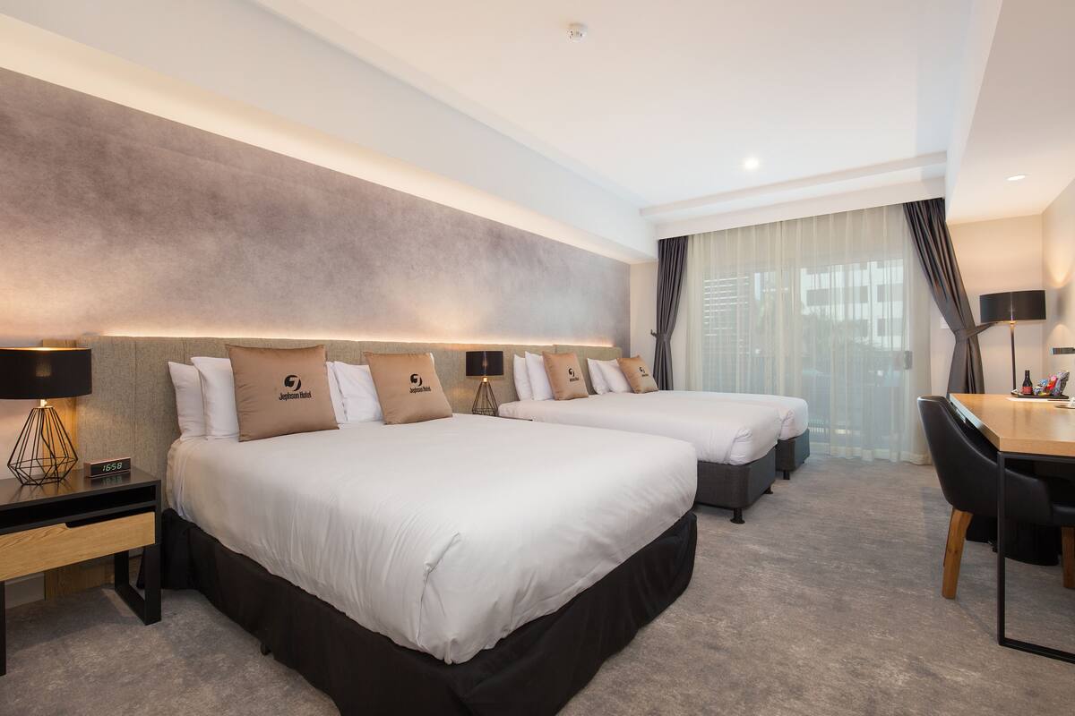 A hotel room with two beds, a desk, and a chair.