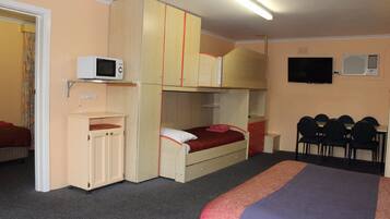 A compact hotel room with bunk beds, a microwave, a TV, and a small desk area.