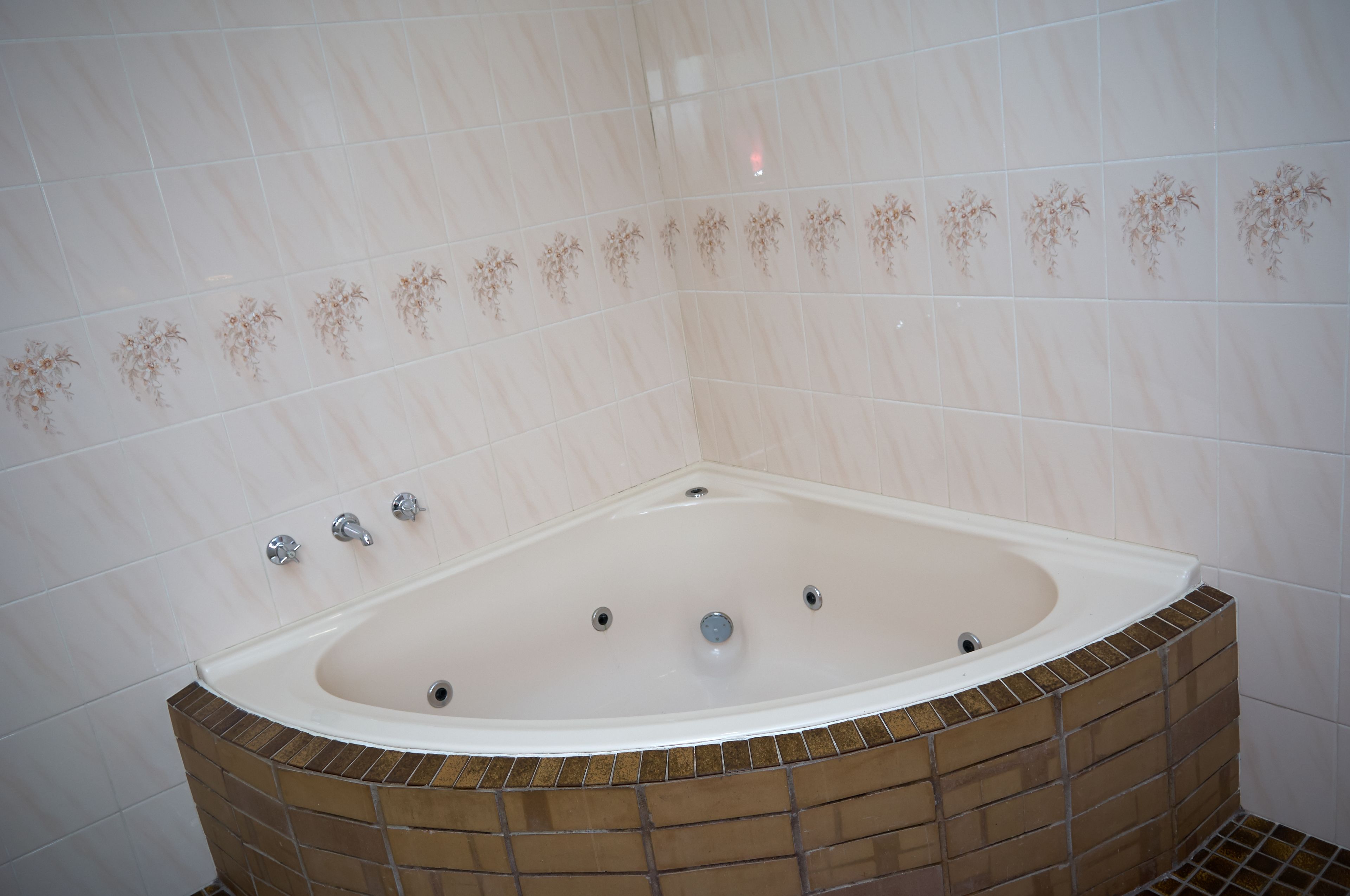 Un baño con una bañera independiente, paredes y piso de azulejos.