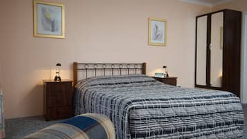 Un dormitorio con una cama, dos mesitas de noche, un armario y dos cuadros en la pared.