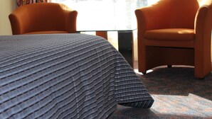 A hotel room with a bed, two orange armchairs, and a glass table. - Motel Mount Gambier (Mount Gambier)