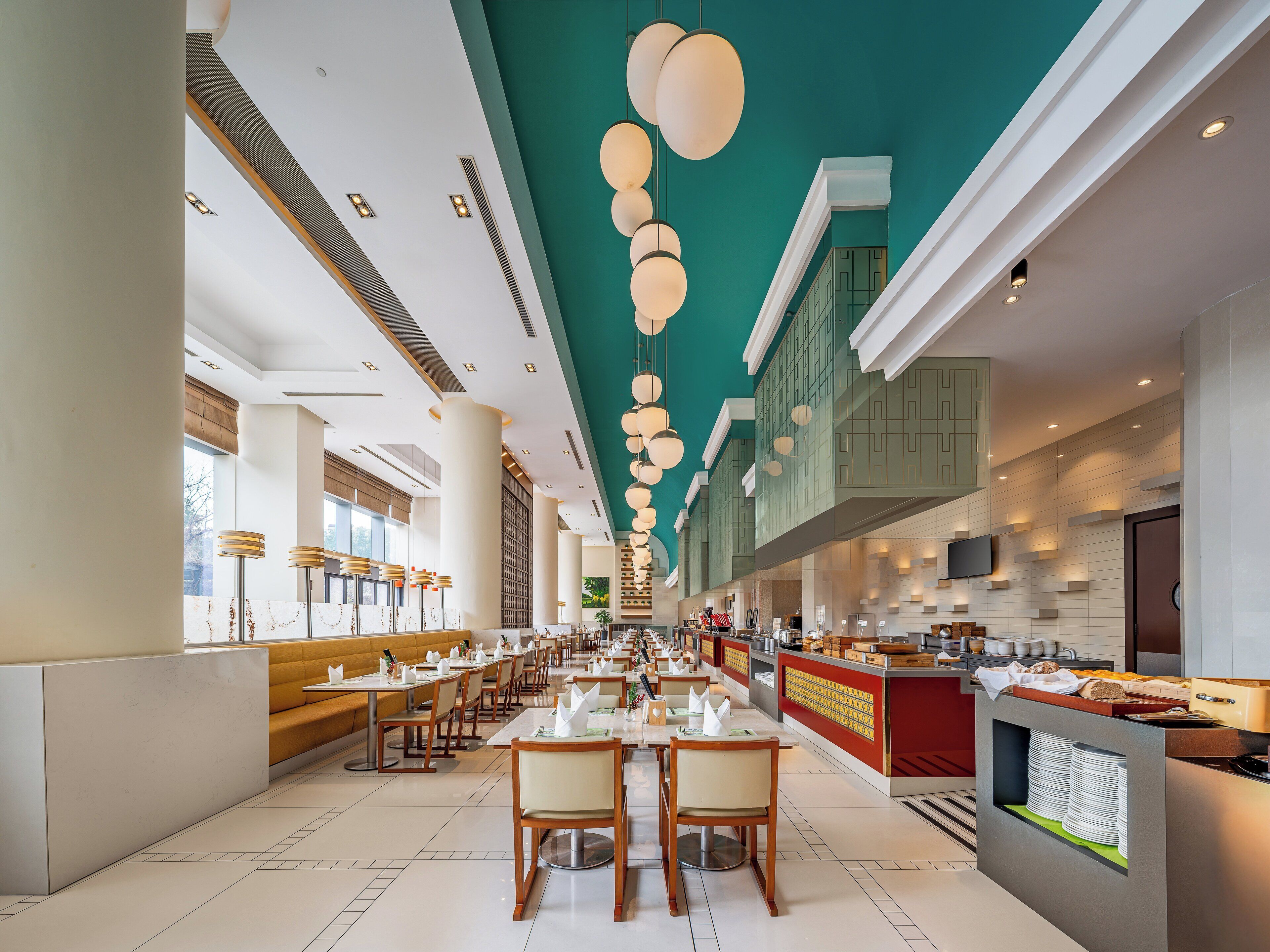 A spacious restaurant with high ceilings, modern lighting, and a long counter with a buffet.