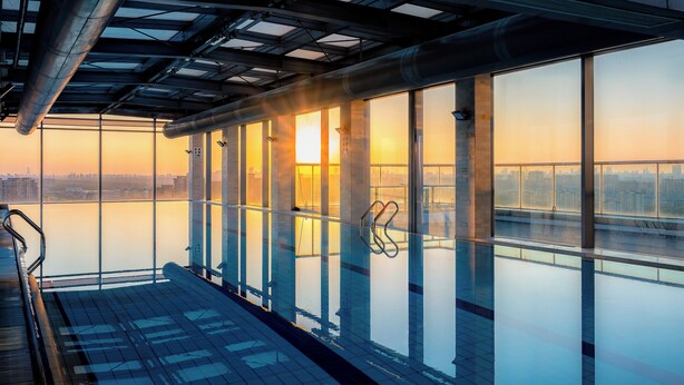 Un rascacielos con amplias ventanas que ofrece vistas a un paisaje urbano al atardecer.
