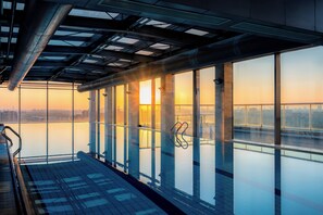 A high-rise building with large windows overlooking a cityscape at sunset. - Holiday Inn Shanghai Pudong Kangqiao by IHG (Shanghai)