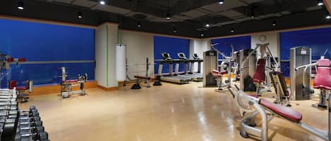 Et fitnesscenter med forskellig træningsudstyr, herunder løbebånd, styrkemaskiner og håndvægte.