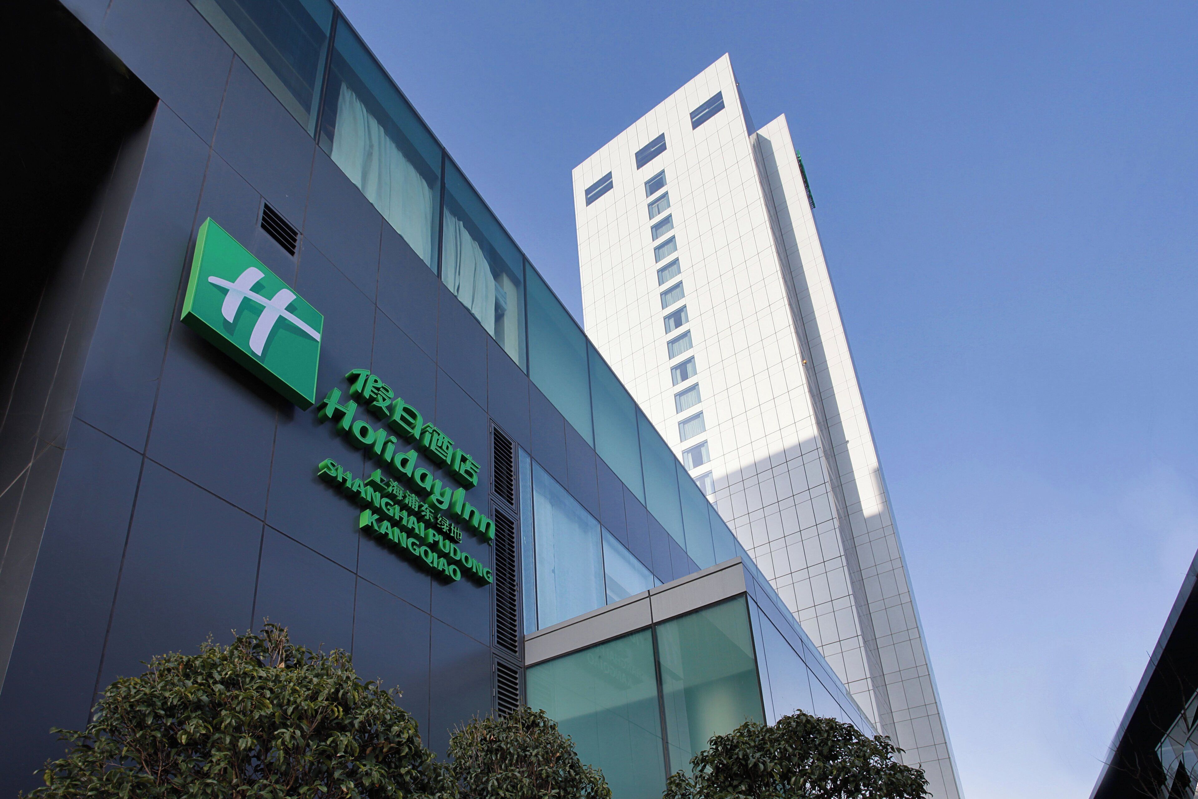 Un edificio moderno con un cartel que indica 'Holiday Inn Shanghai Pudong Kangqiao'.