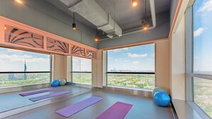 Um quarto amplo com grandes janelas, colchonetes e bolas de exercício.
