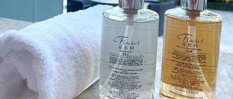 Two bottles of shampoo and shower gel on a table with a white towel.