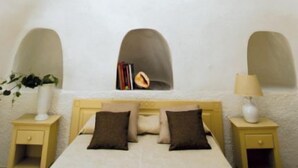 Un dormitorio acogedor con cama, mesitas de noche y un rincón de lectura pequeño con libros.