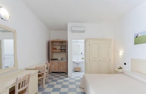A bedroom with a checkered floor, a bed, a desk with chairs, a wardrobe, and a mirror. - Hotel Due Passi dal Pizzo (Gallipoli)