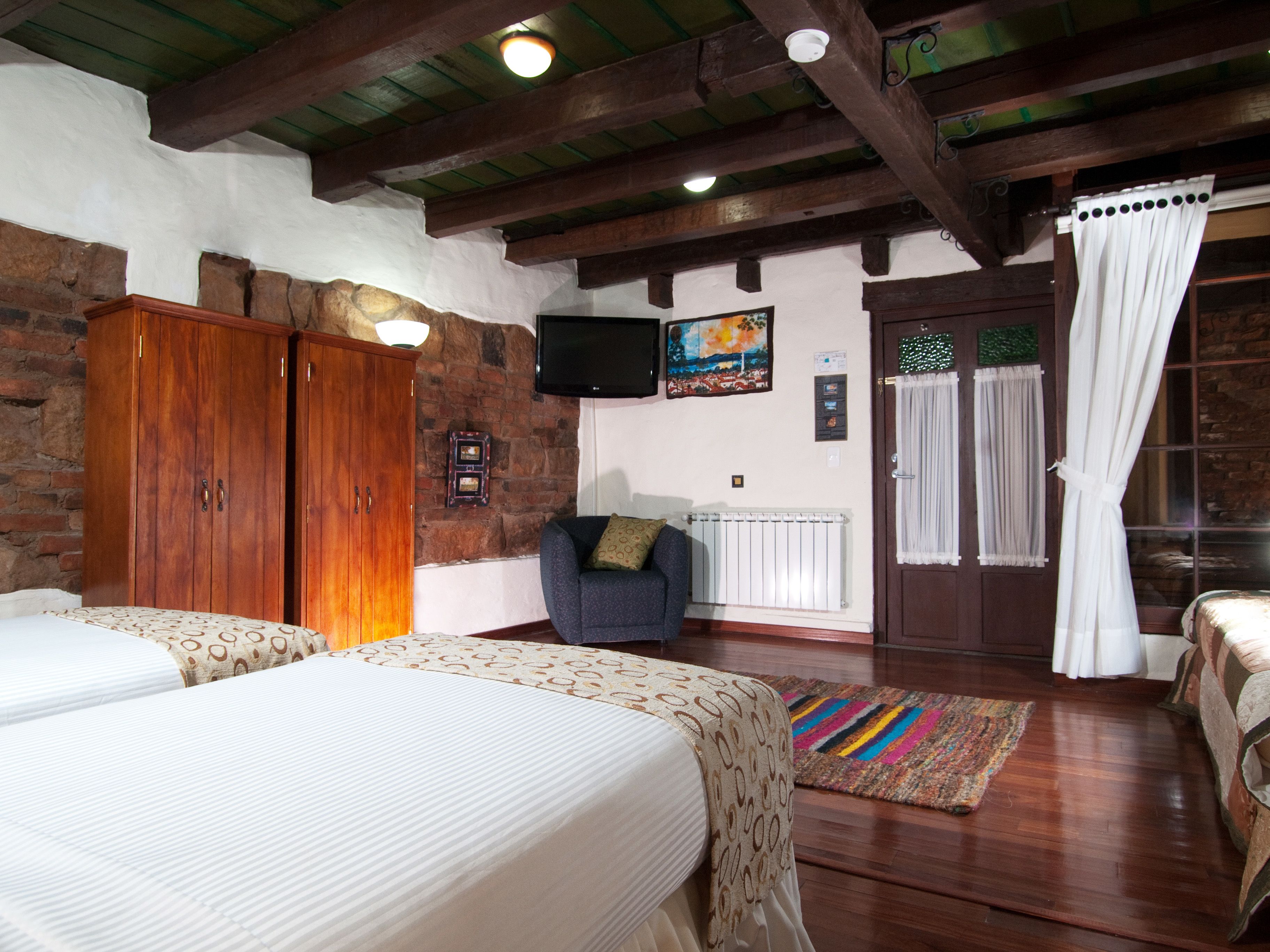 Una habitación acogedora con dos camas, un armario de madera, un televisor y un cuadro en la pared.