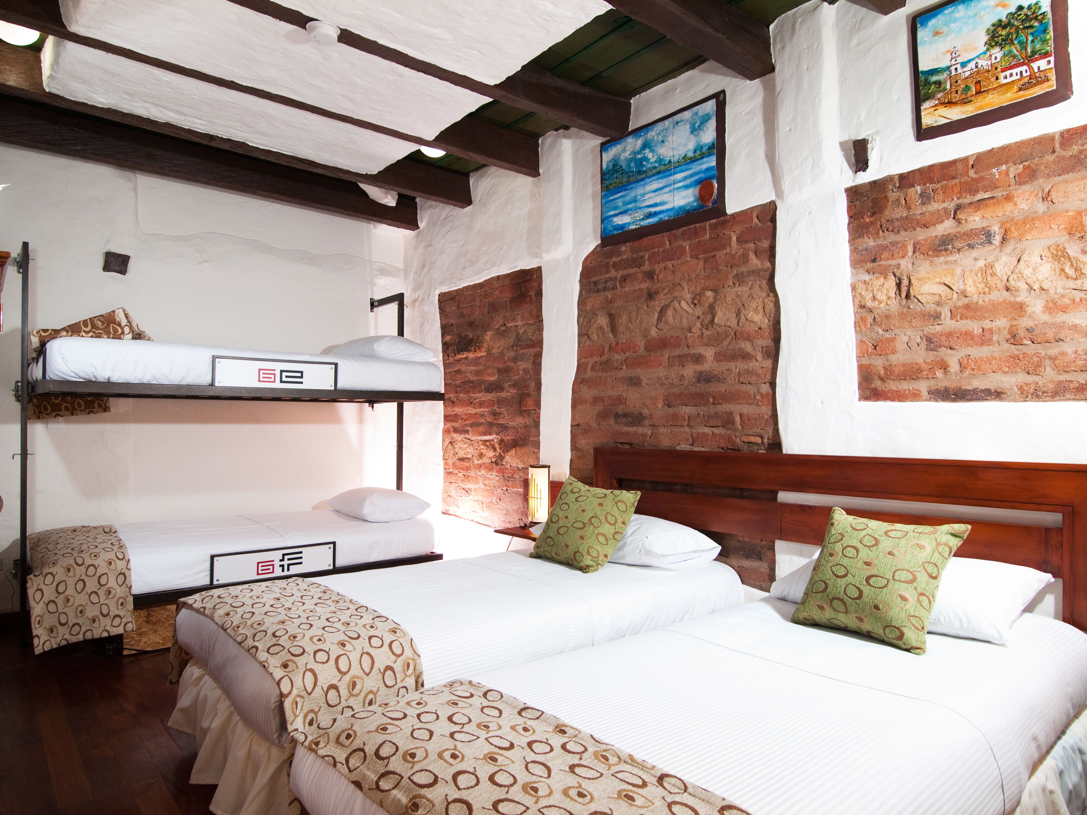 A room with bunk beds, a brick wall, and a painting.
