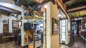 A rustic bar area with wooden beams, shelves with bottles, and a chalkboard menu. - Hotel Muisca (Bogotá)