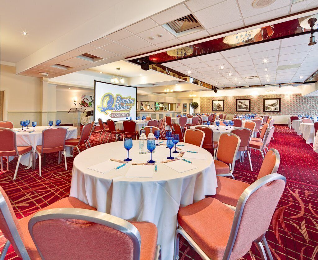 A conference room with round tables, orange chairs, and a large screen displaying the Marriott logo.