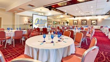 A conference room with round tables, orange chairs, and a large screen displaying the Marriott logo.