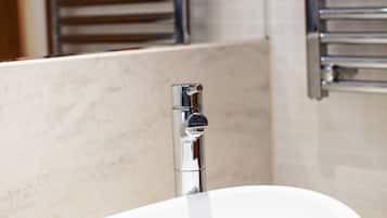 A modern bathroom with a white sink, chrome faucet, and a towel rack mounted on the wall.