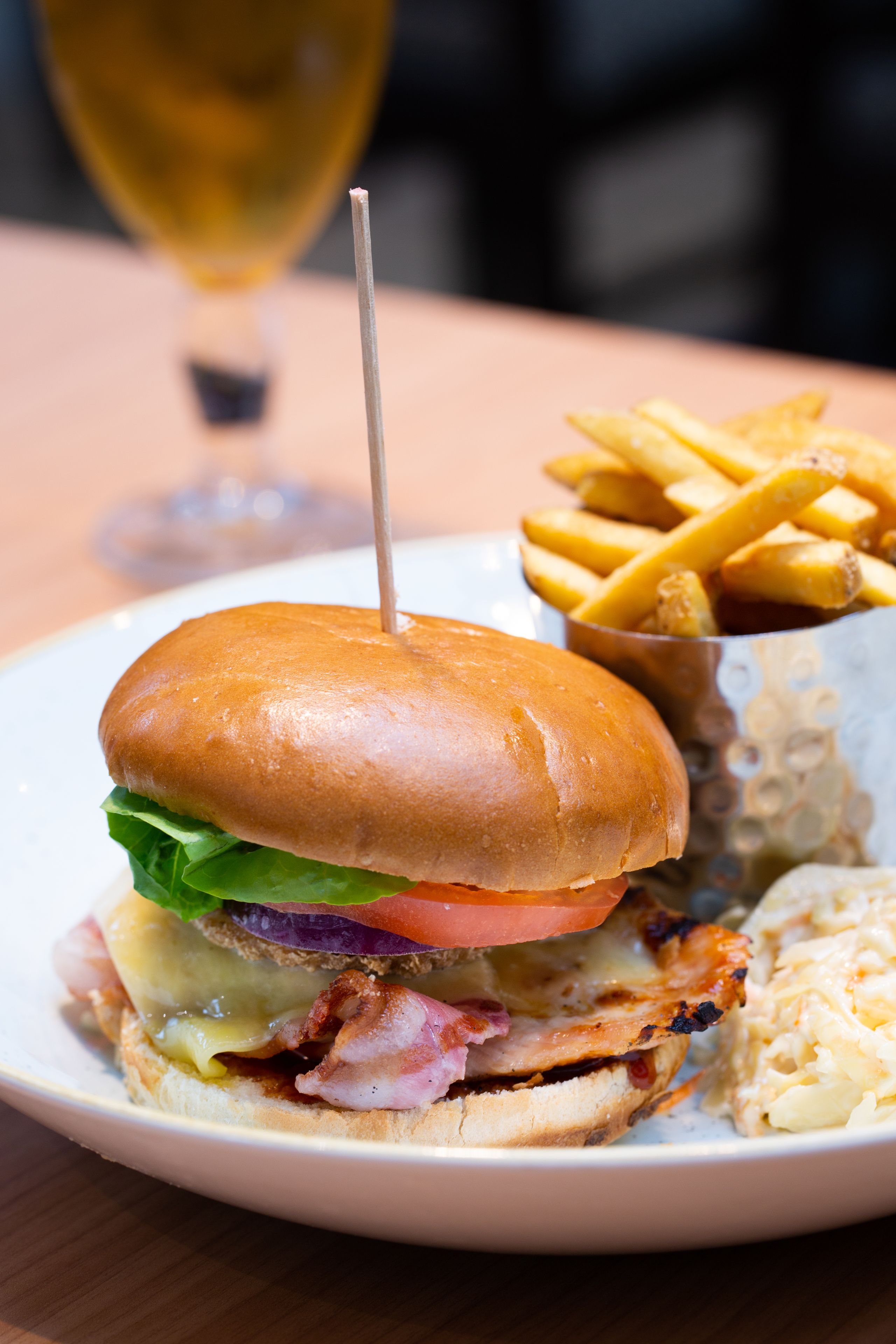 Un sándwich con un palillo, papas fritas y una copa de vino sobre un plato.