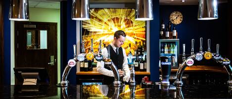 A bar area with multiple taps, including Guinness, and a clock on the wall.