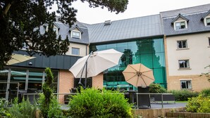 A modern building with large windows and a covered outdoor seating area with umbrellas. - Drayton Manor Hotel (Tamworth)