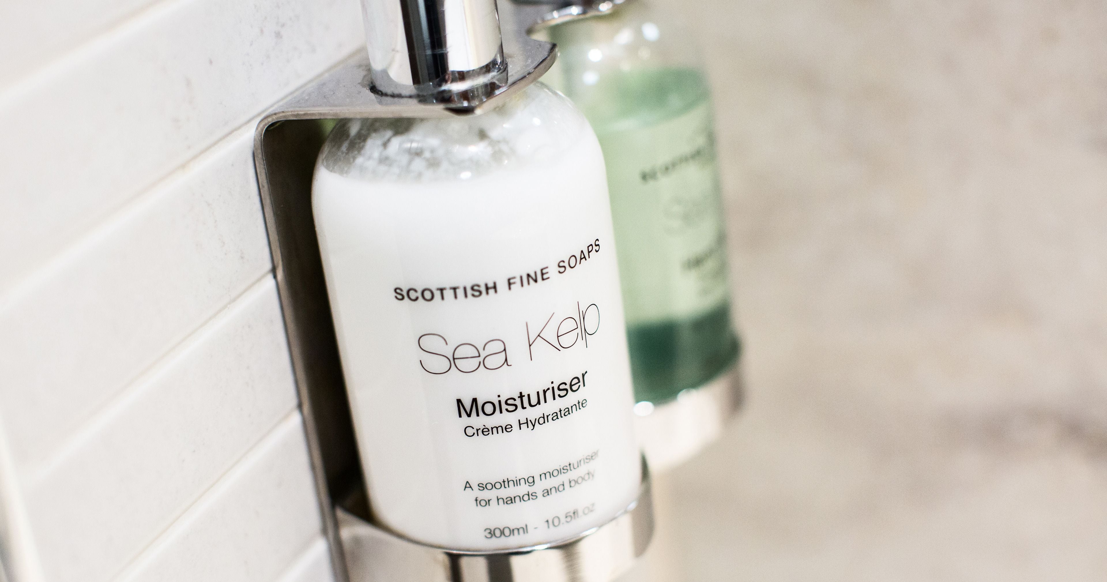 A bottle of Sea Kelp Moisturiser from Scottish Fine Soaps, 300ml, next to a green bottle.
