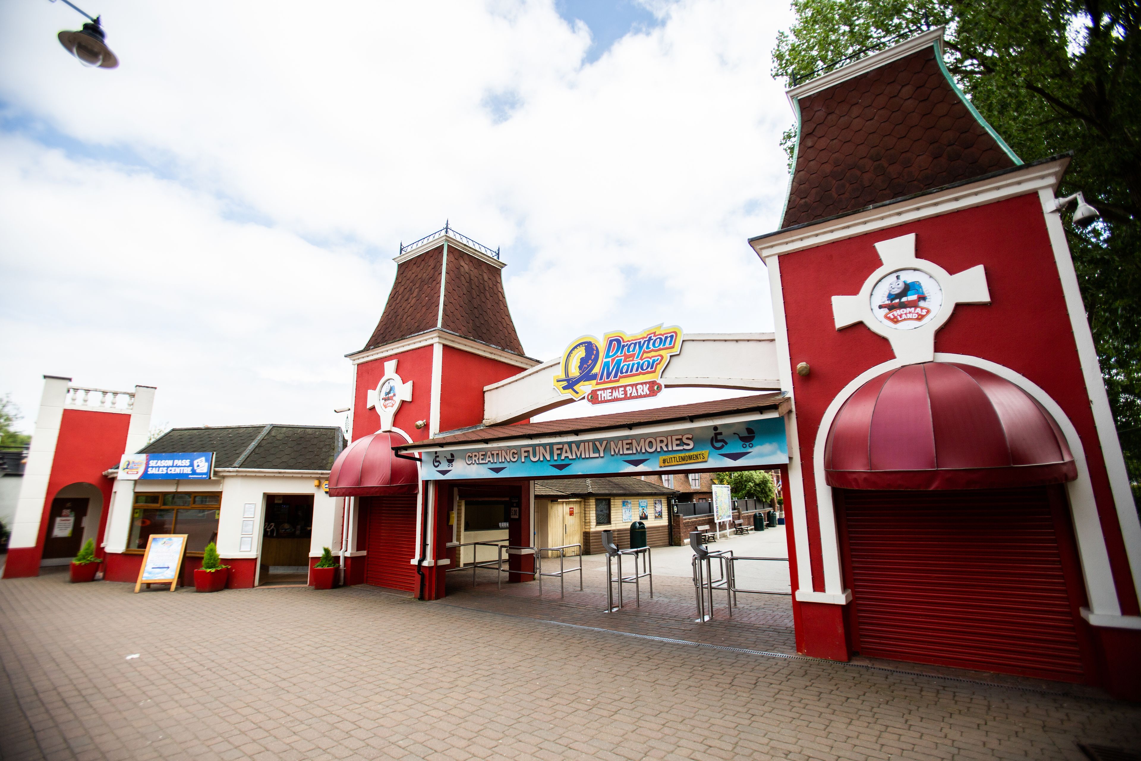 A theme park entrance with a red and white building, a sign for 'Drayton Manor', and a 'Season Pass Sales Centre'.