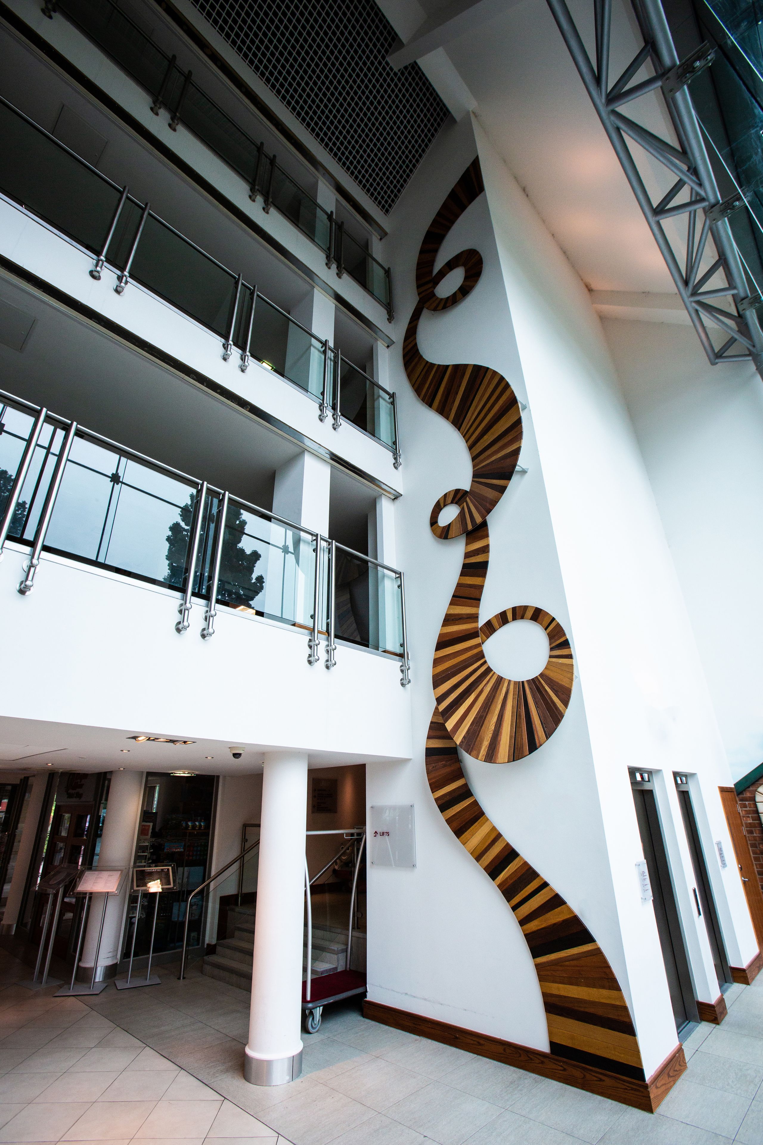 A multi-level interior with a distinctive spiral wall design, glass railings, and a staircase.