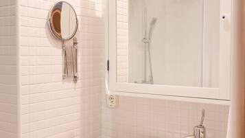Un baño con lavamanos blanco, espejo y ducha.