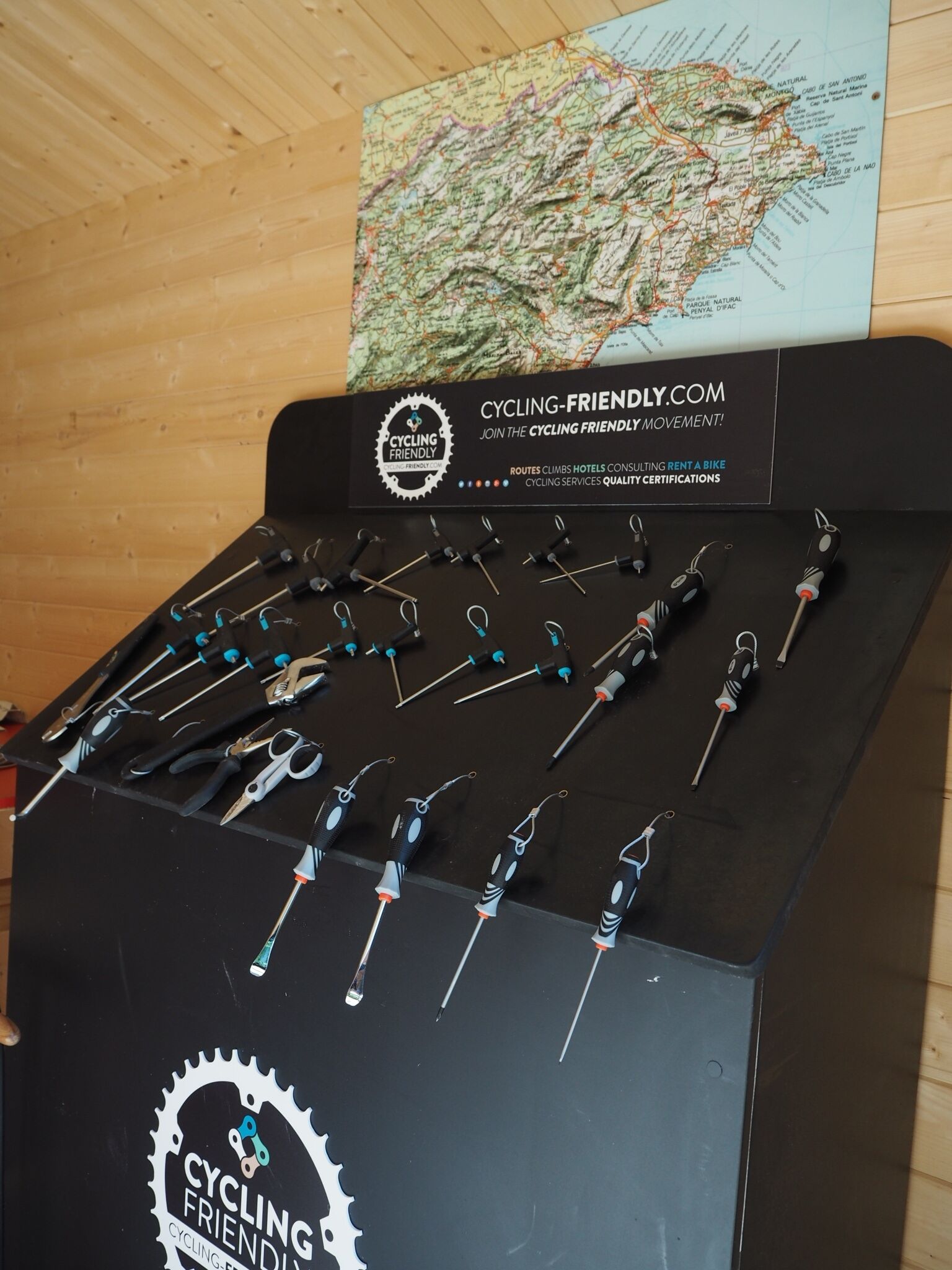 Exhibición de herramientas para bicicleta y un mapa sobre una pared de madera.