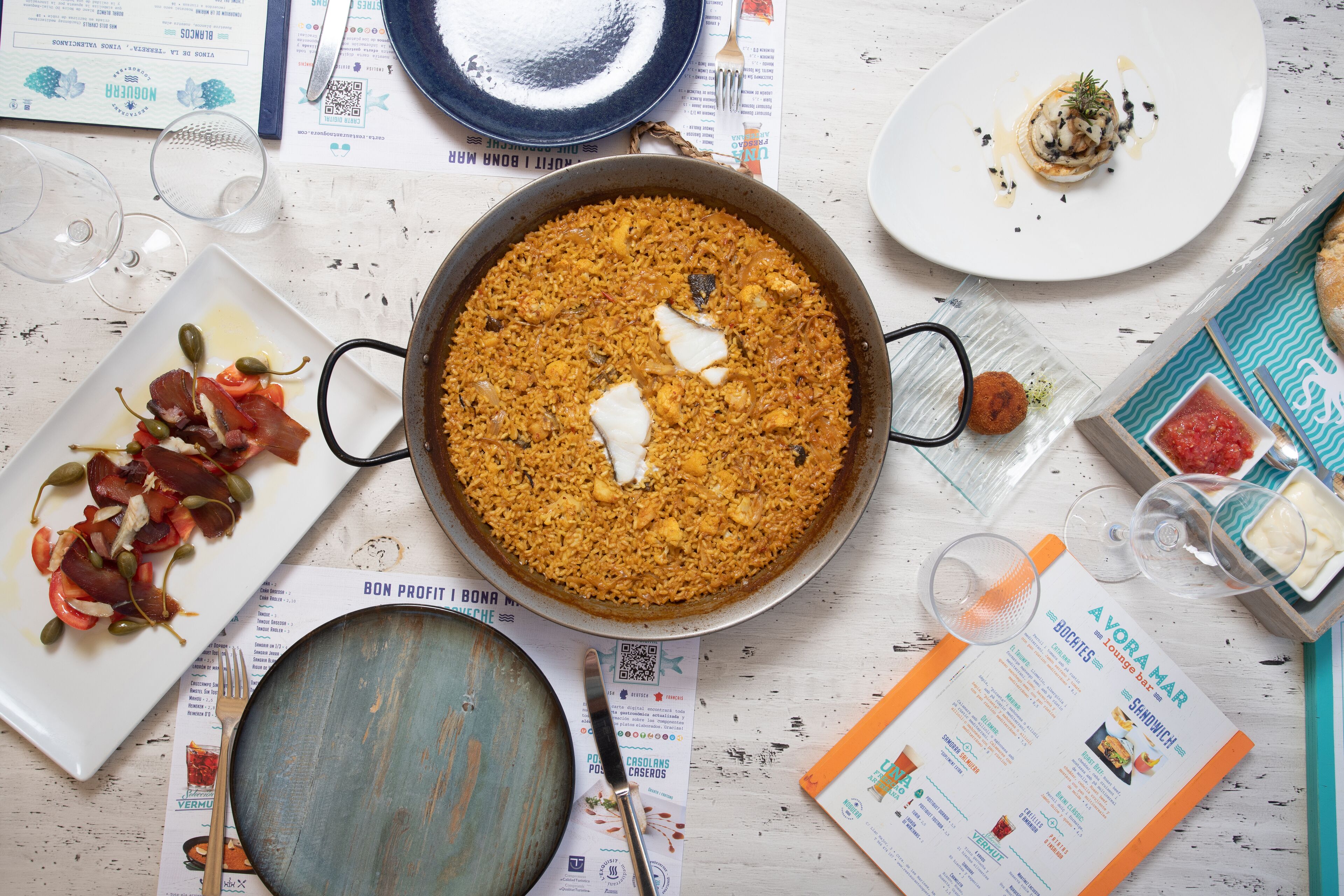 A table with a large pan of rice, various plates with food, and a menu.
