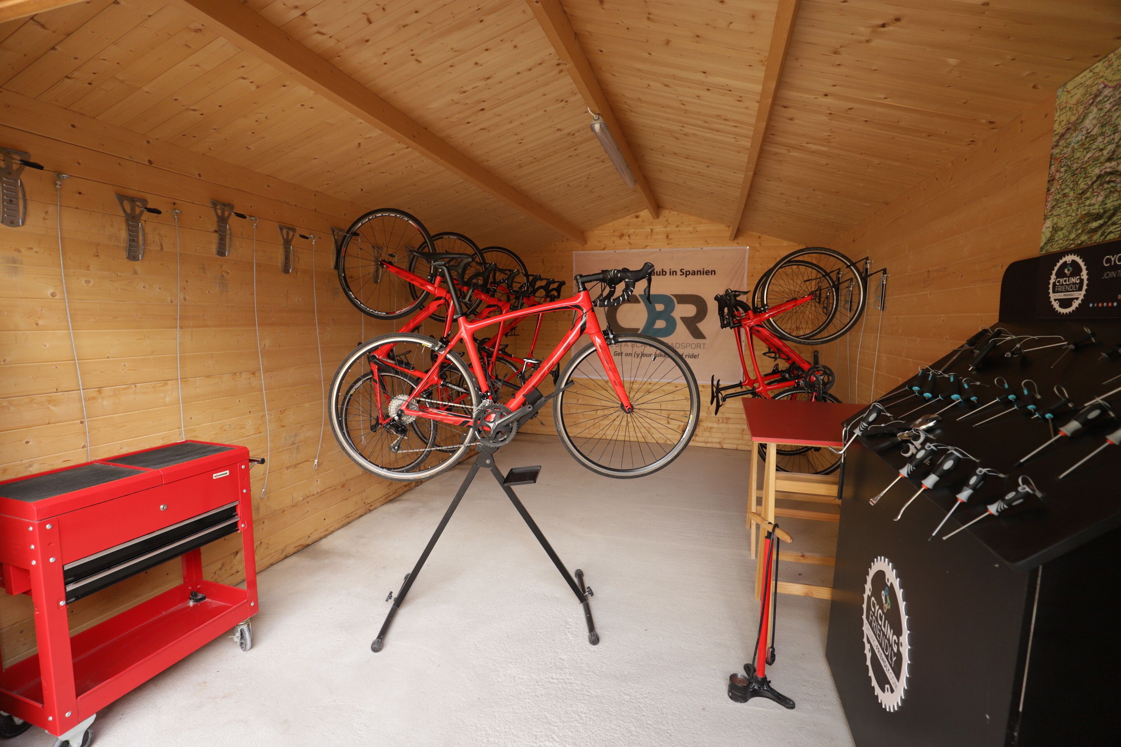 A wooden ceiling, a red bicycle on a stand, a red tool chest, and a wall-mounted sign.