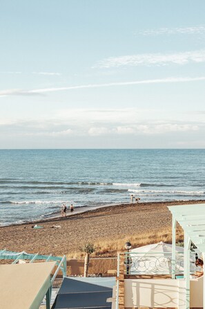 A beach view with a clear sky, a sandy shore, and a few people walking. - Noguera Mar Hotel (Denia)