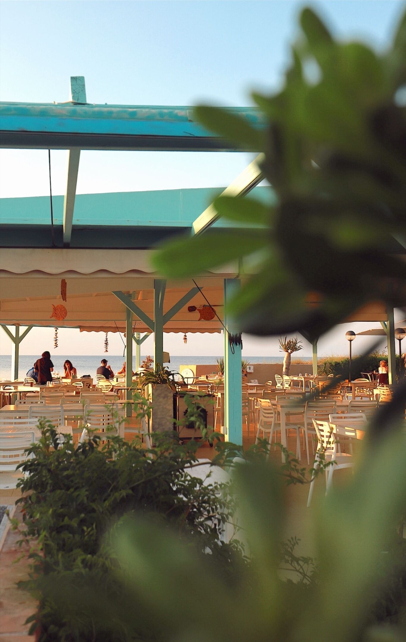 An outdoor seating area with tables and chairs, overlooking the sea.