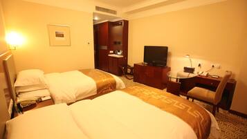 A hotel room with two beds, a desk, a television, and a bathroom visible through an open door.