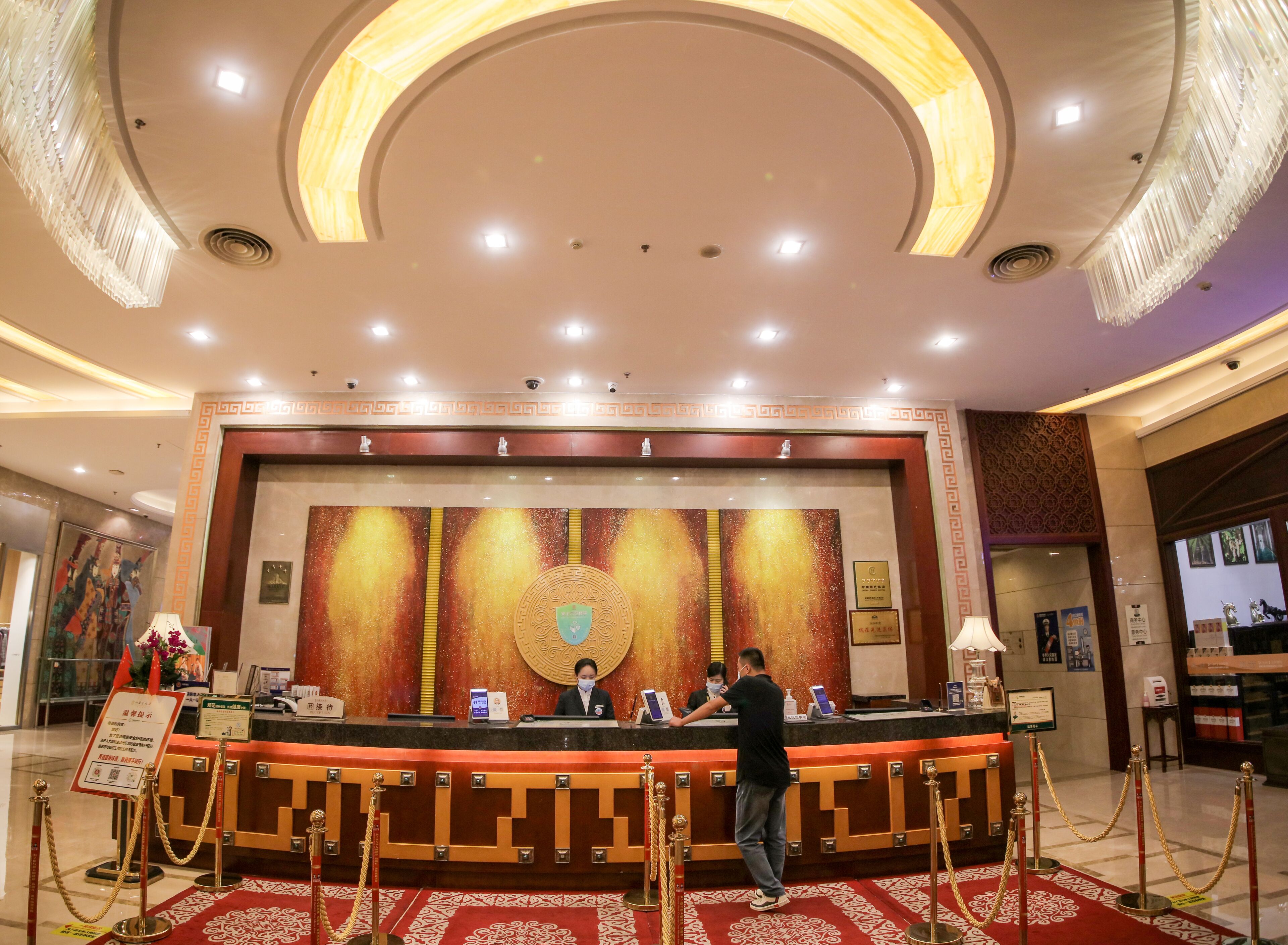 Zona de recepción de un hotel con mostrador, escritorio y un amplio muro decorativo.