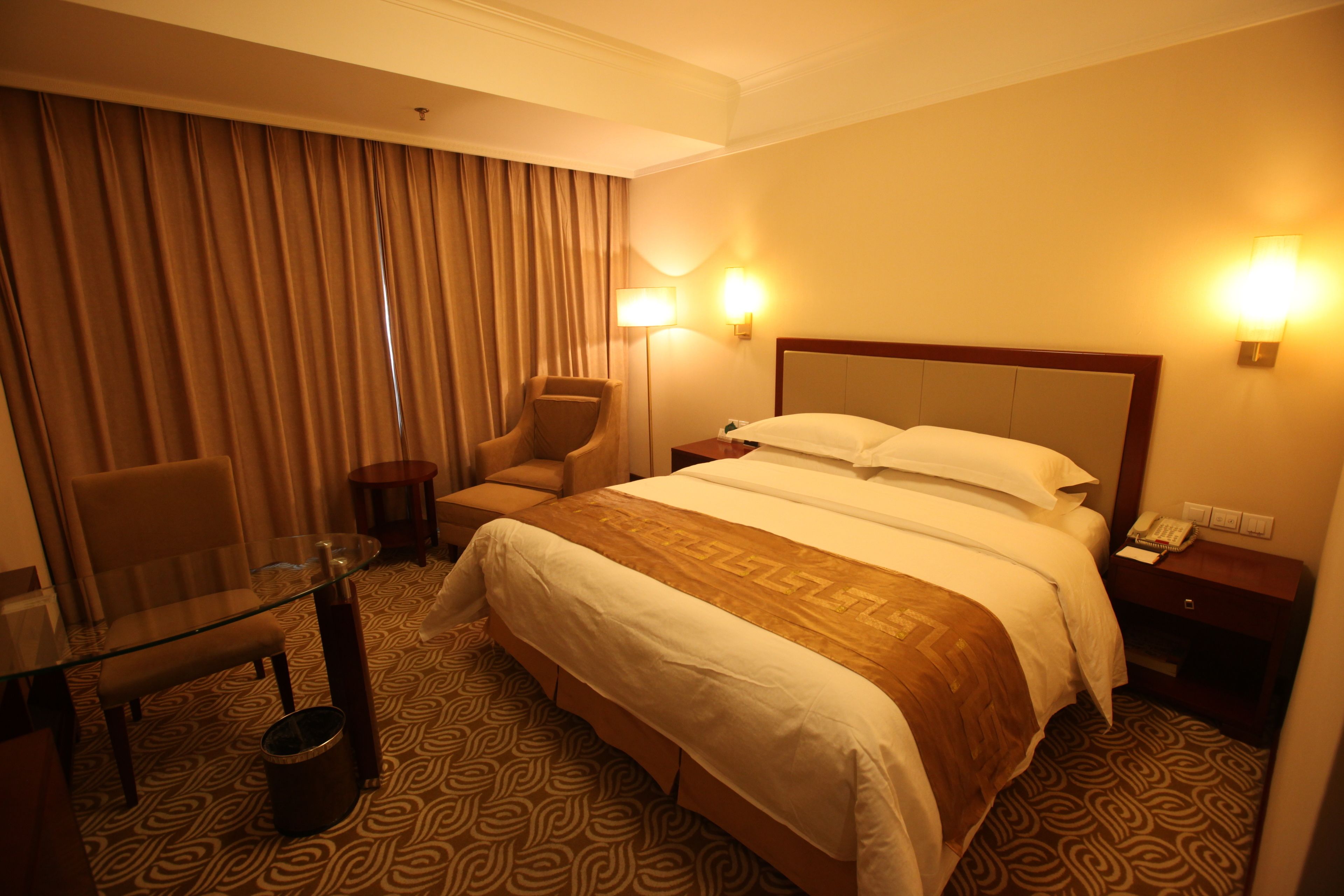 Une chambre d’hôtel avec un grand lit, une table en verre, une chaise et un bureau.