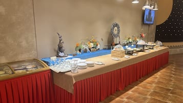 Montaje de bufé con una mesa larga, cristalería y arreglos florales.