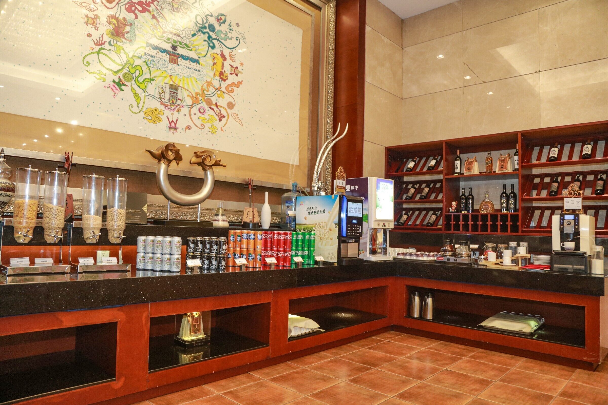 A hotel reception area with a counter, beverage dispensers, and a display of bottled water and soda.