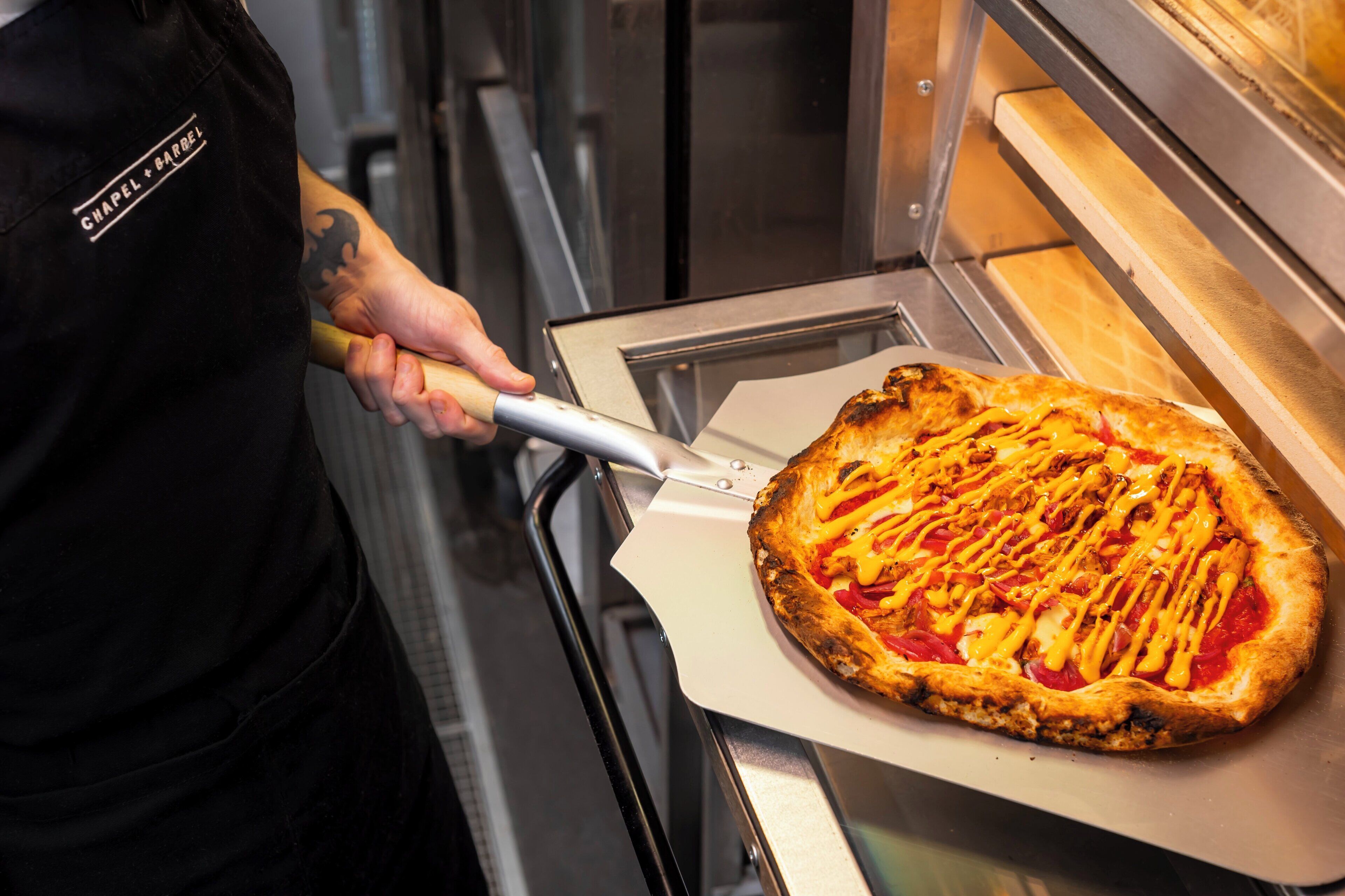 A pizza being removed from an oven with a spatula.