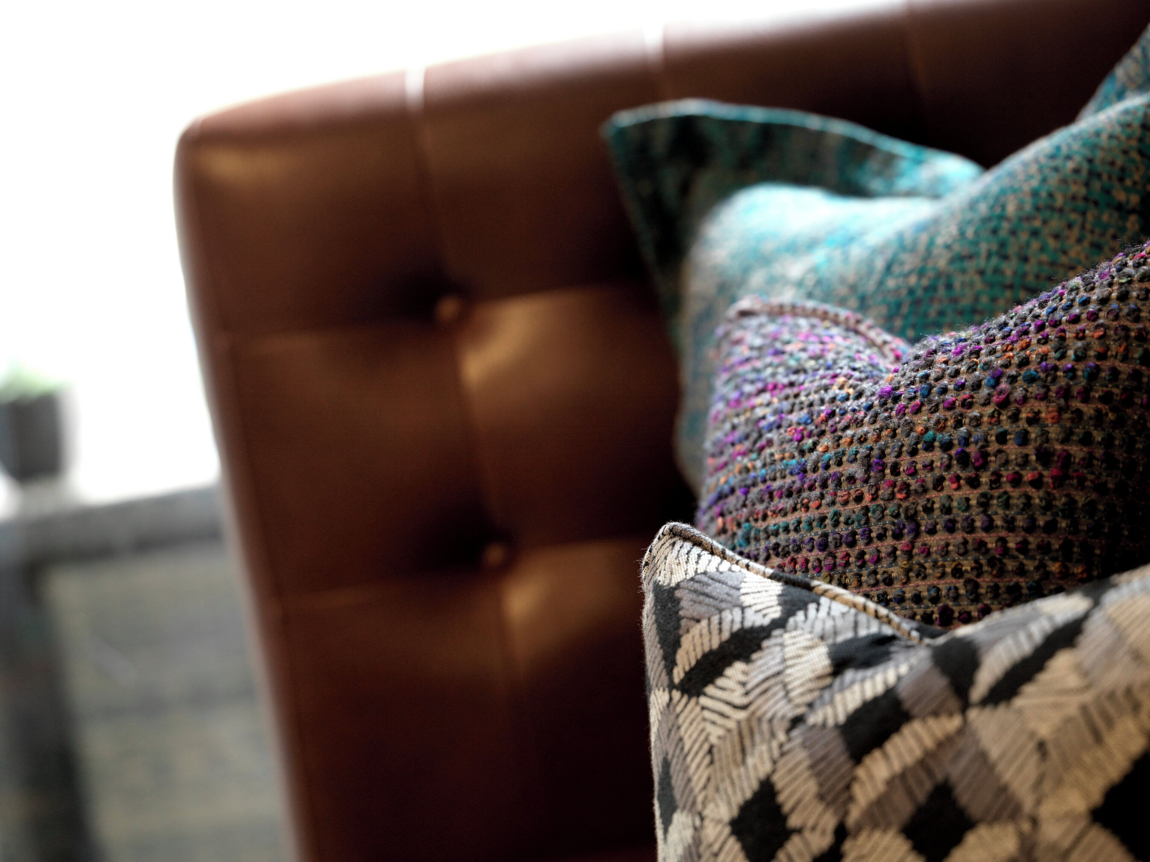 A tufted leather chair with a patterned cushion.