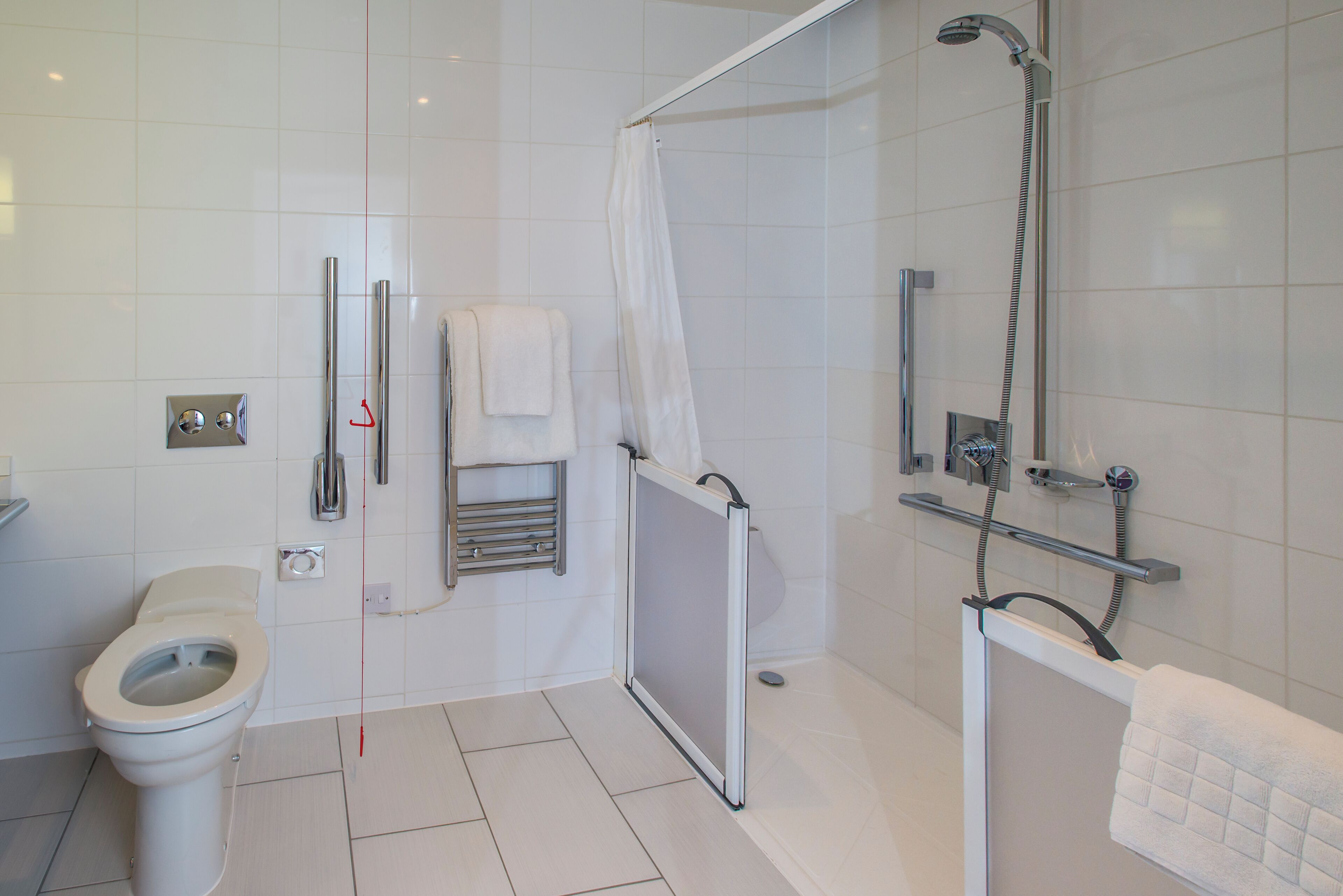 A modern bathroom with a toilet, shower, and a towel rack.